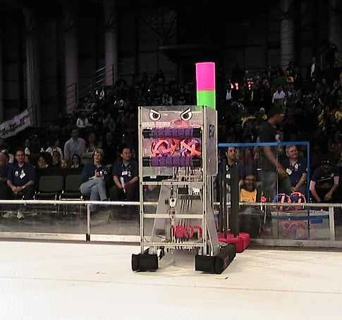 ニューヨークで開催された 2009 FIRST ロボティクス コンテストの観客の前に立つアリーナに立つ、背の高い長方形のロボット。