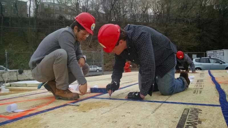 スティーブンス研究所のSURE HOUSEの学生が床に気密テープを貼っている様子