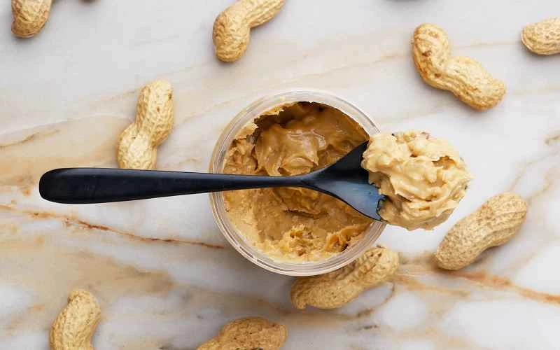 ピーナッツバターの瓶にスプーン一杯のピーナッツバター